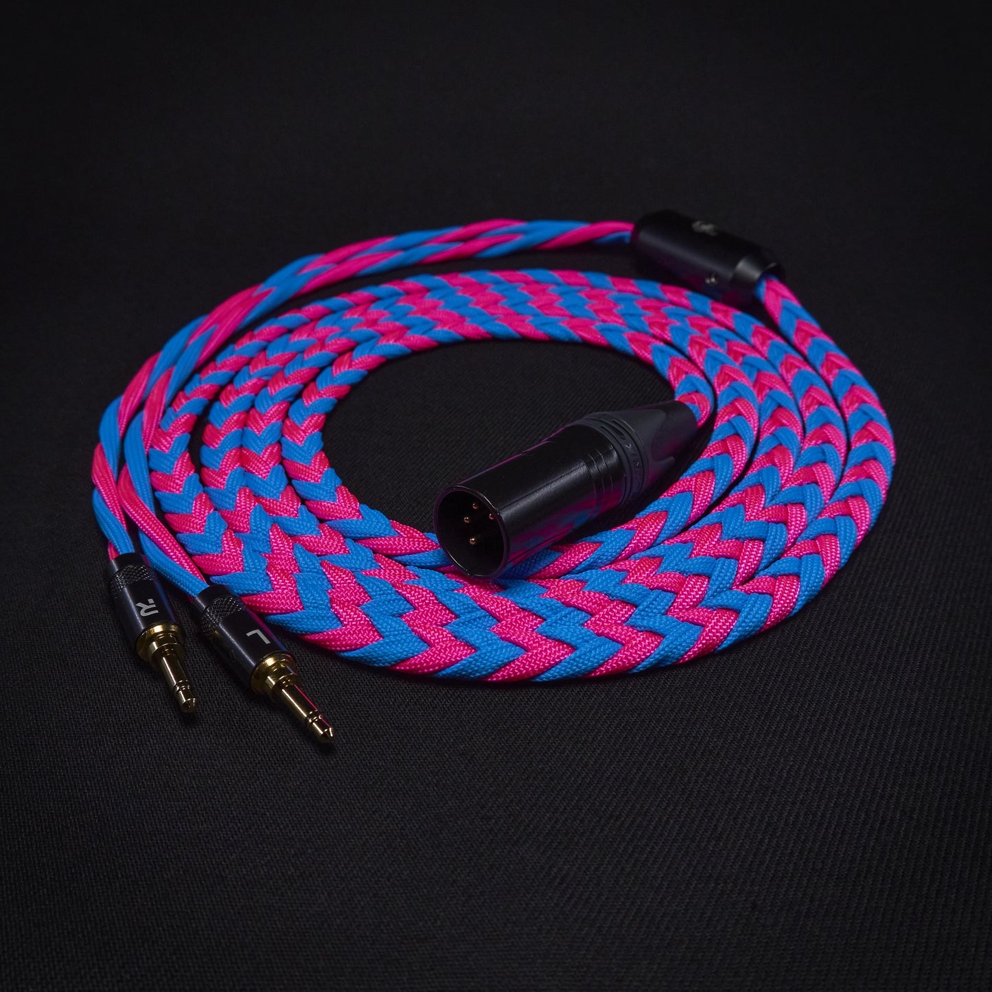 Braided audio cable with pink and blue pattern on a black background