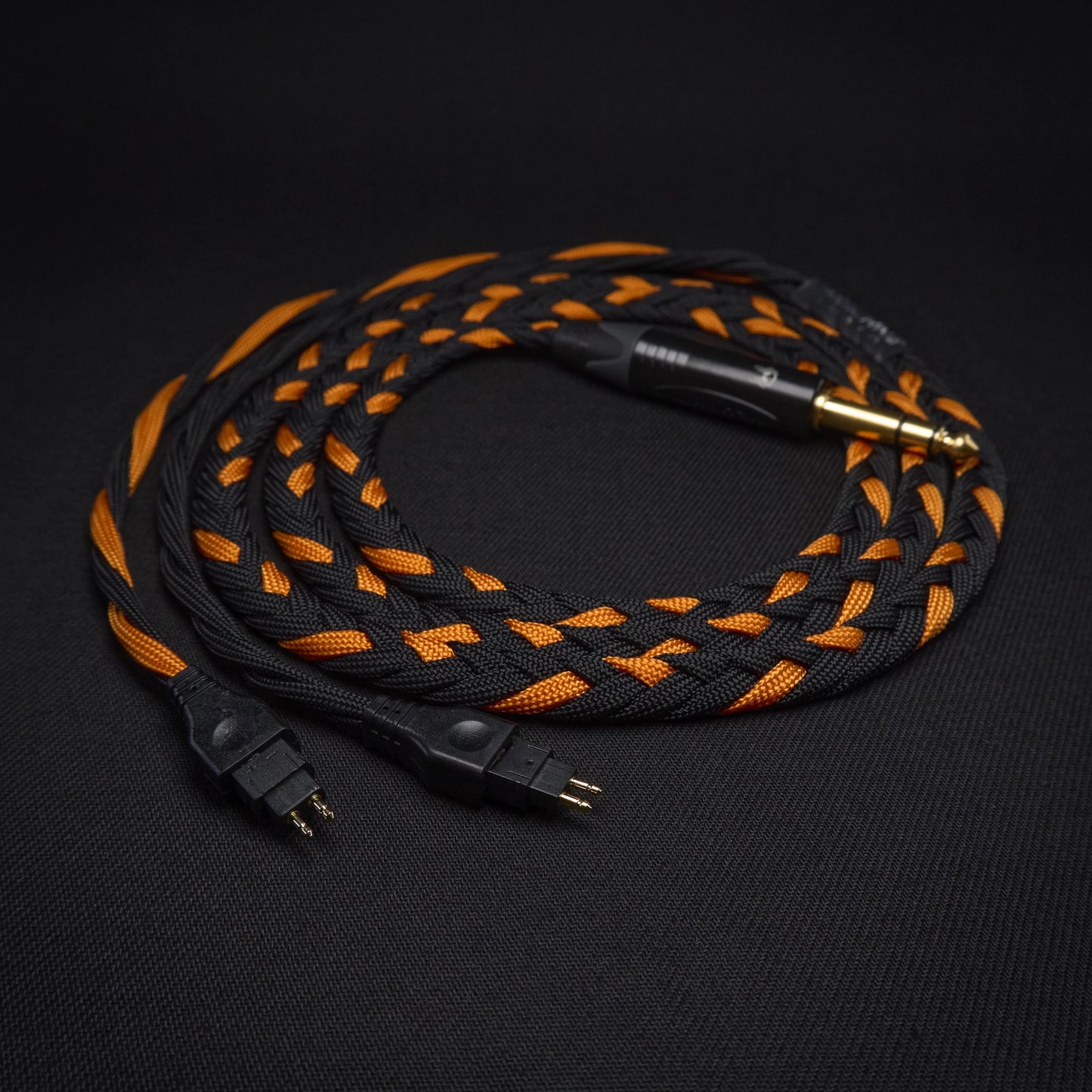 Braided audio cable with black and orange design on a dark background