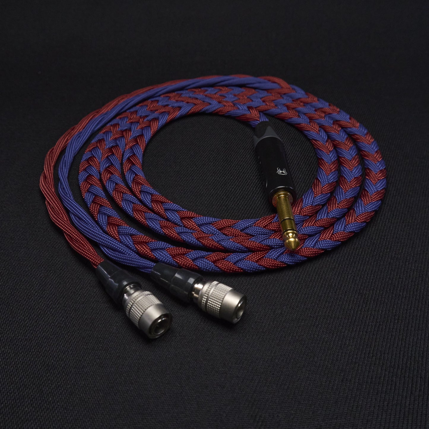Braided audio cable with gold and silver connectors on a black background