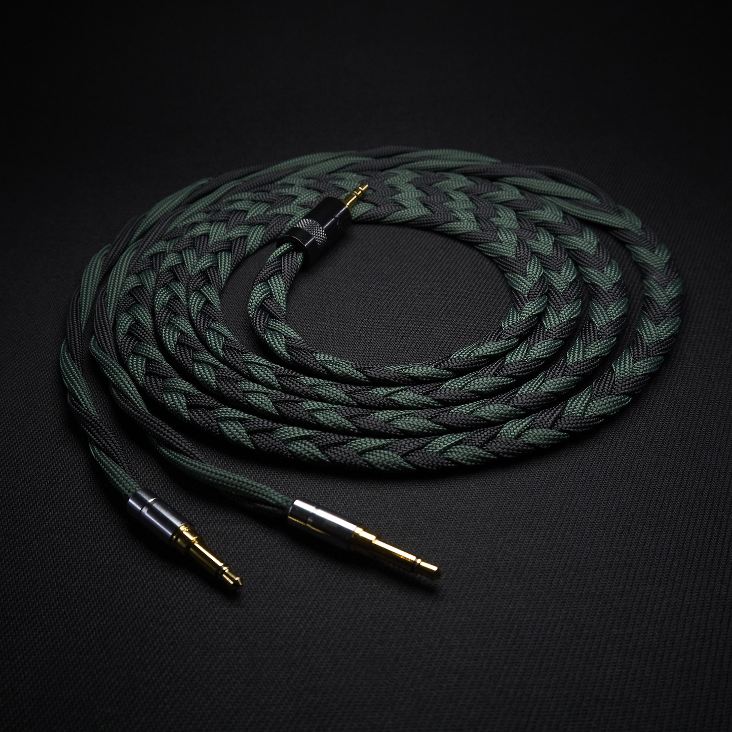 Coiled braided audio cable with gold connectors on a black background