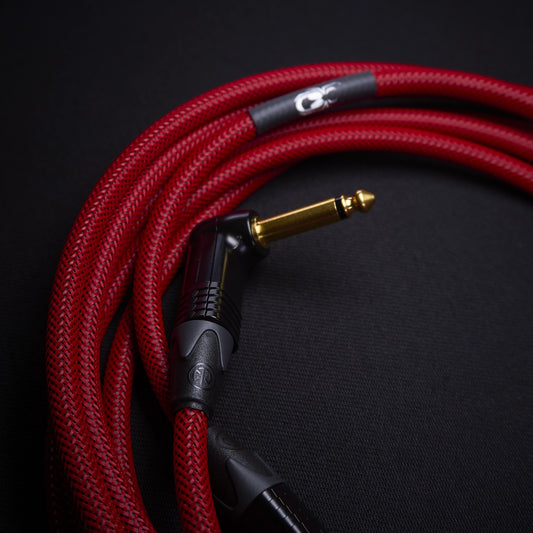 Red braided cable with a black and gold connector on a dark background