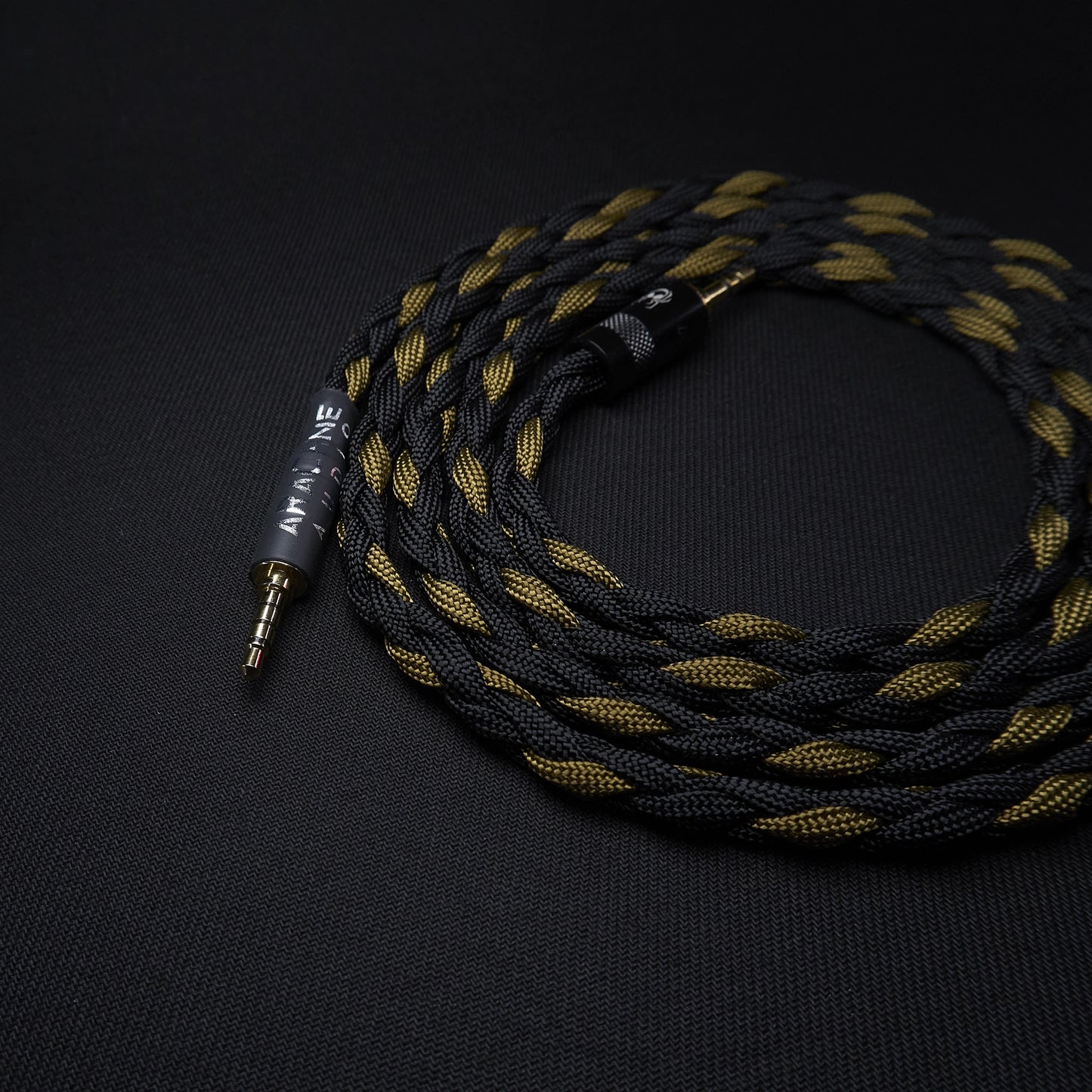 Braided audio cable with gold and black color scheme on a dark background
