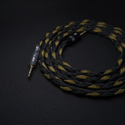 Braided audio cable with gold and black color scheme on a dark background
