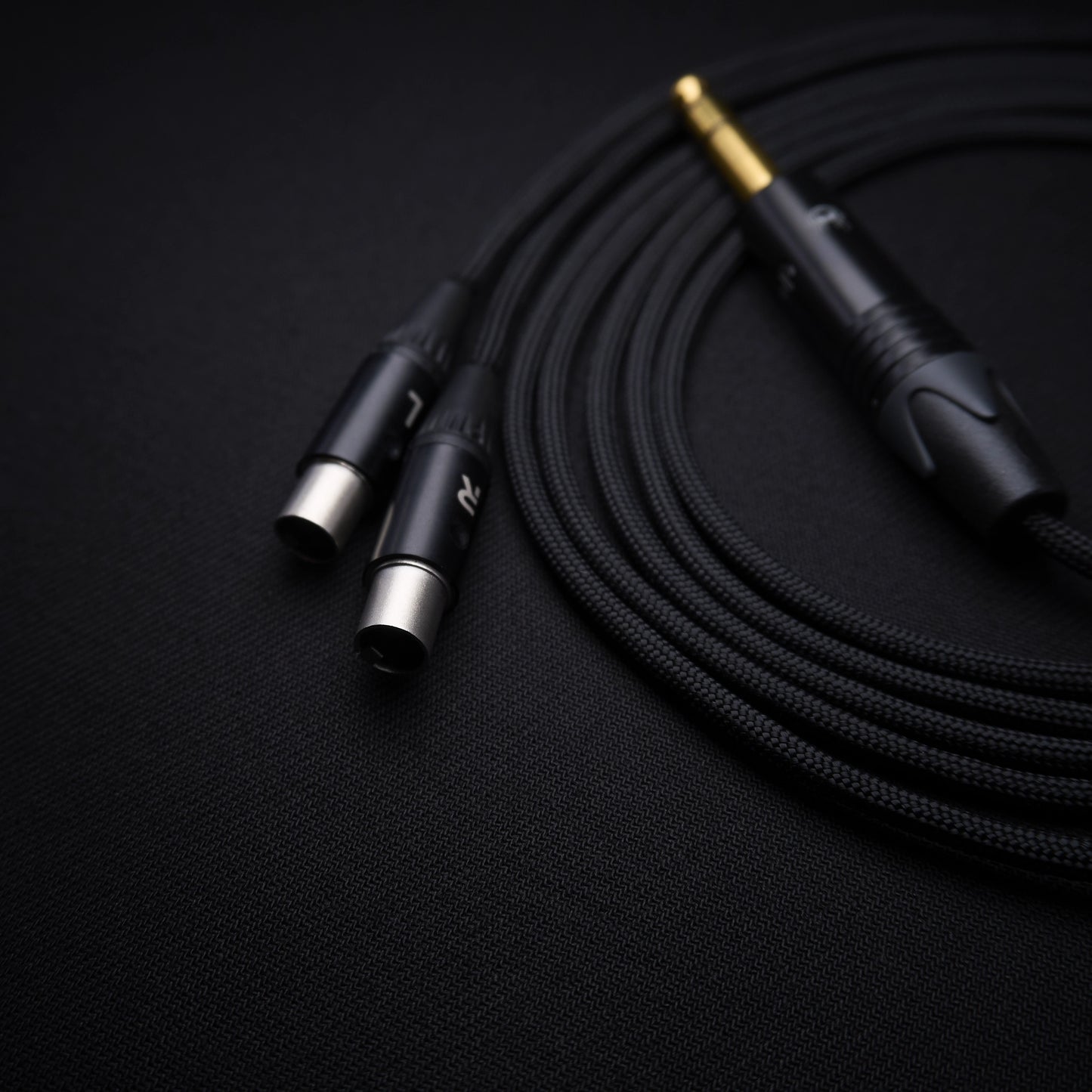 Black audio cable with three different connectors on a black background