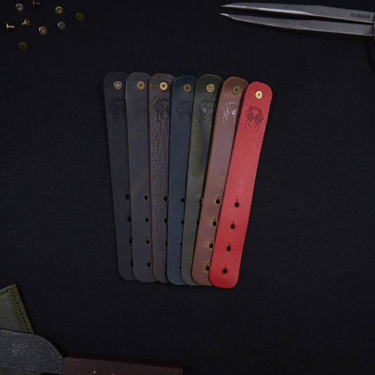 Range of Fermata leather cable straps in seven colours (black, grey, brown, teal, olive, tan, red) with brass studs and embossed Arachne spider, hand-cut in Tallinn.