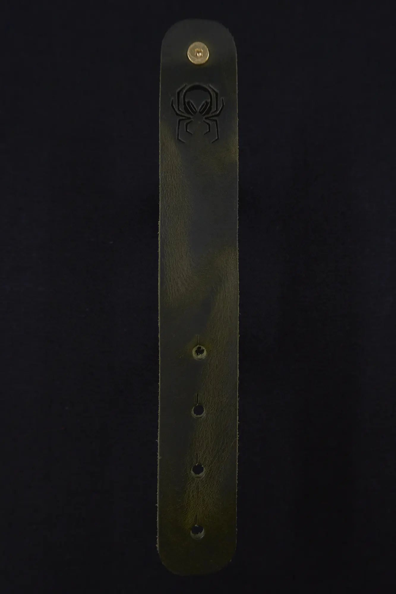 Fermata leather cable strap in Fir (dark green) with brass stud and embossed Arachne spider