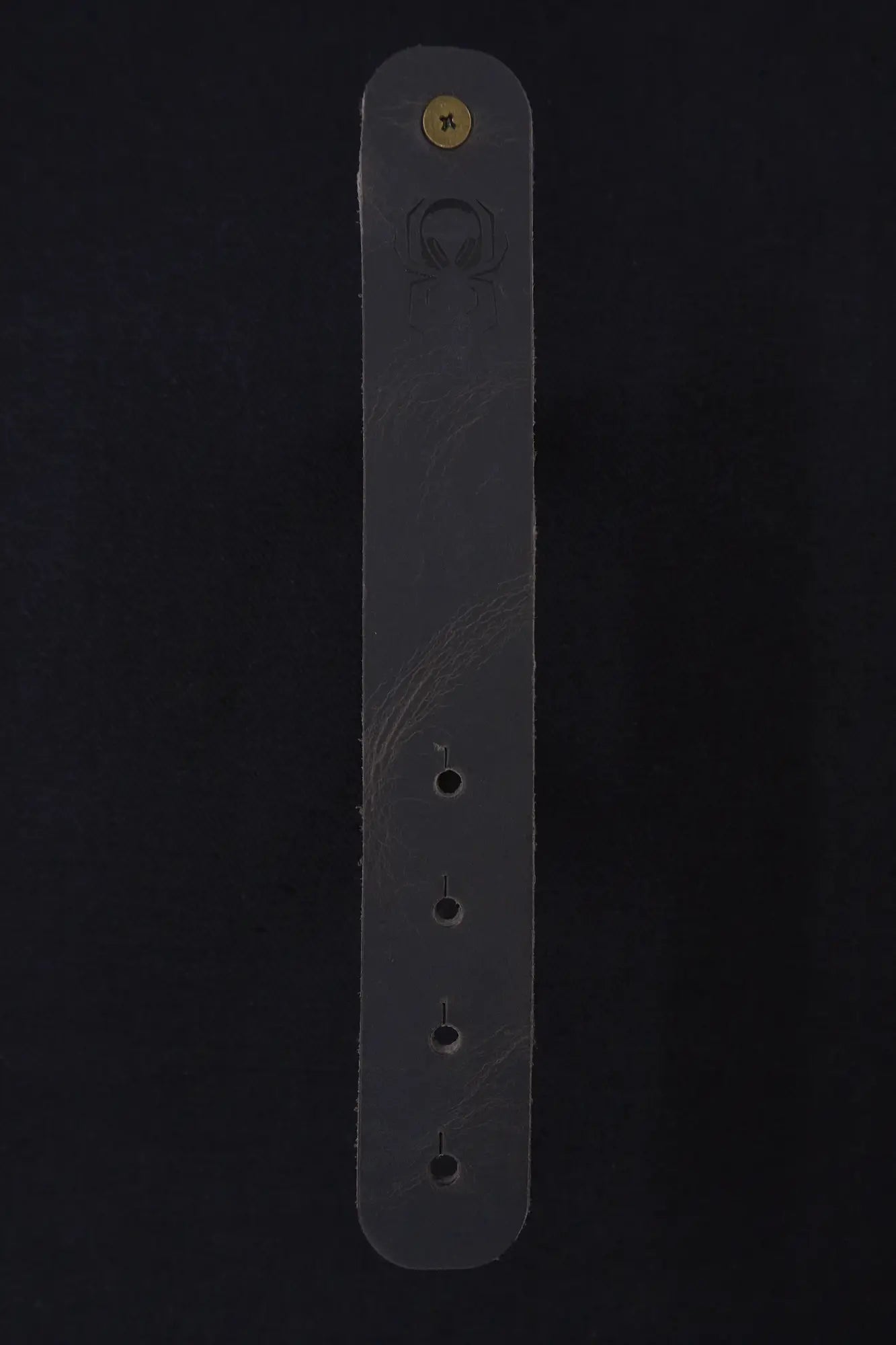 Fermata leather cable strap in Graphite (grey) with brass stud and embossed Arachne spider