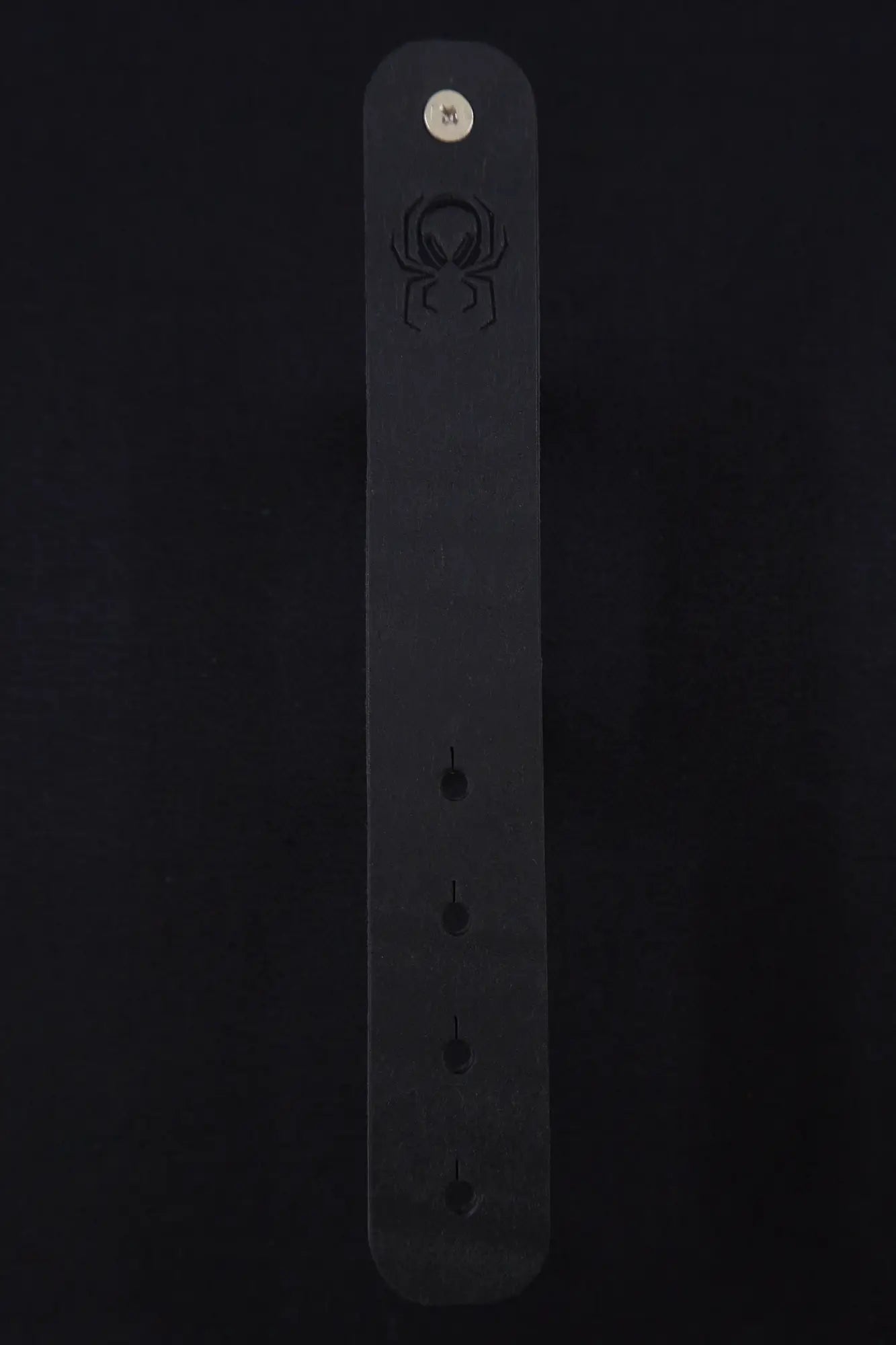 Fermata leather cable strap in Onyx (Pueblo black) with brass stud and embossed Arachne spider