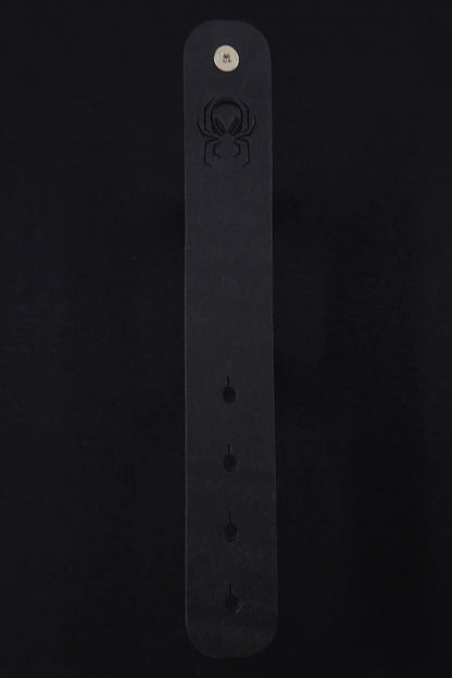Fermata leather cable strap in Onyx (Pueblo black) with brass stud and embossed Arachne spider