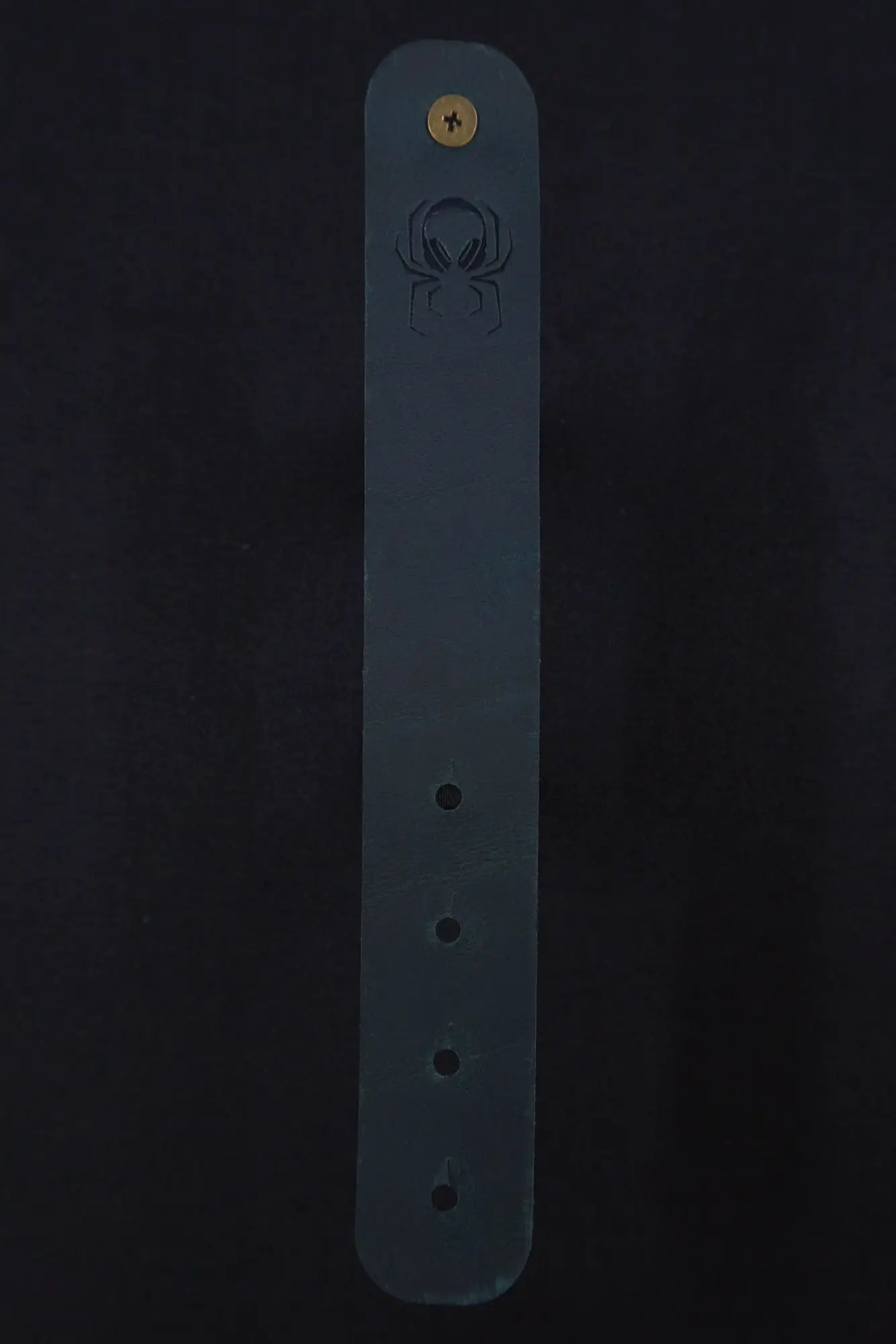 Fermata leather cable strap in Verdigris (teal) with brass stud and embossed Arachne spider