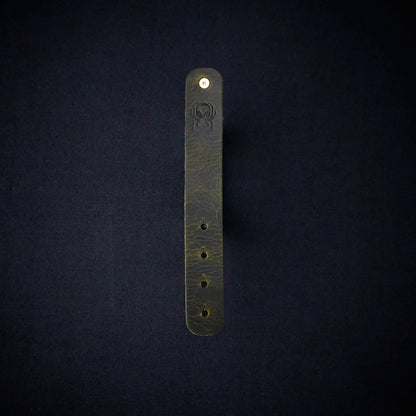 Fermata leather cable organizer in Fir (dark green) with brass stud and embossed Arachne spider