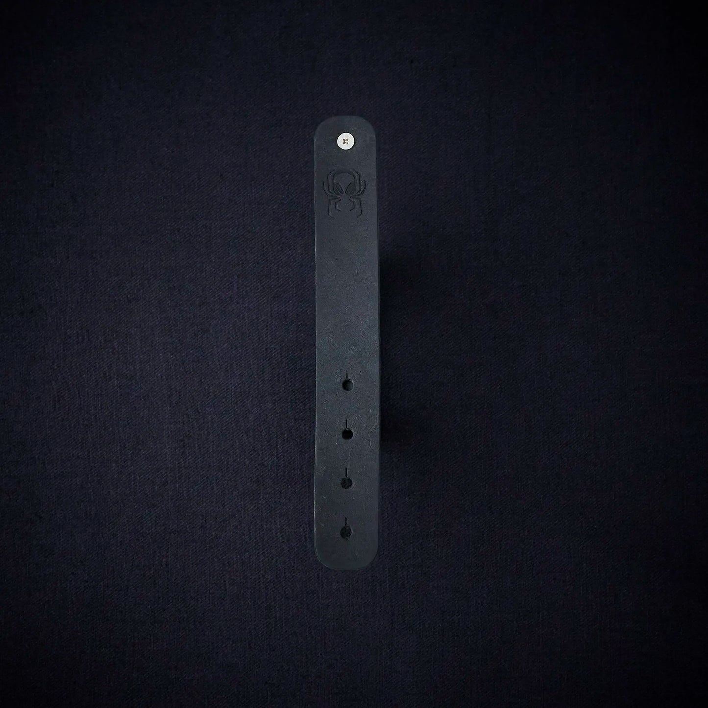 Fermata leather cable organizer in Onyx (Pueblo black) with brass stud and embossed Arachne spider
