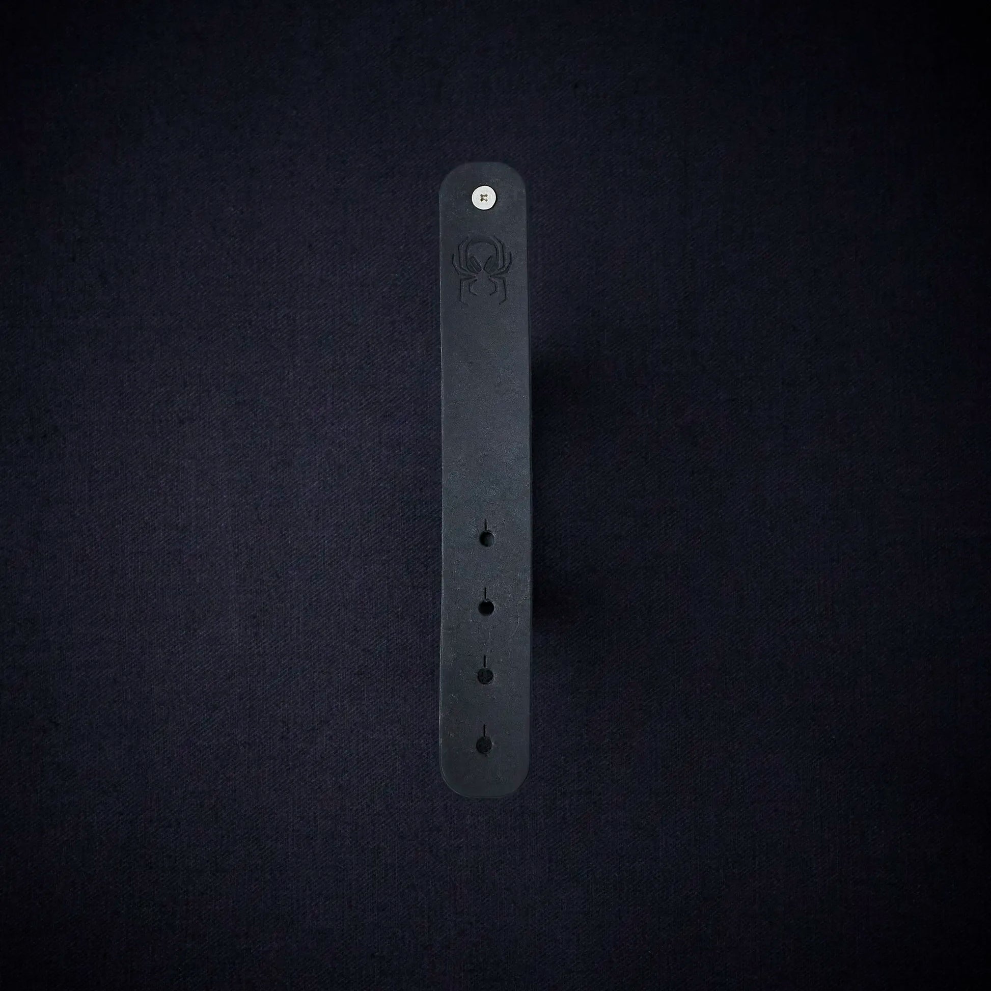 Fermata leather cable organizer in Onyx (Pueblo black) with brass stud and embossed Arachne spider