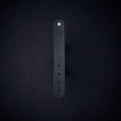 Fermata leather cable organizer in Onyx (Pueblo black) with brass stud and embossed Arachne spider