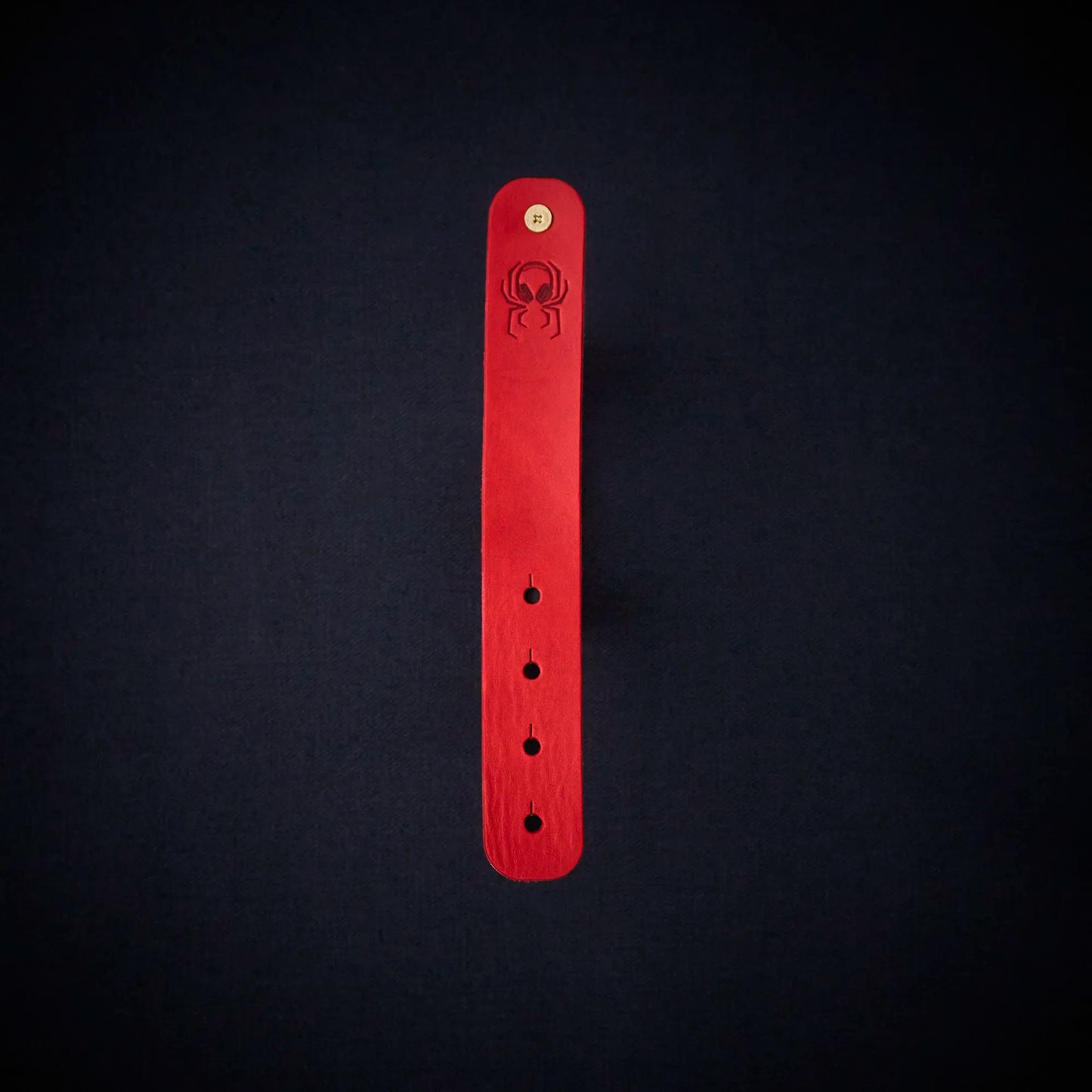 Fermata leather cable organizer in Oxblood (red) with brass stud and embossed Arachne spider