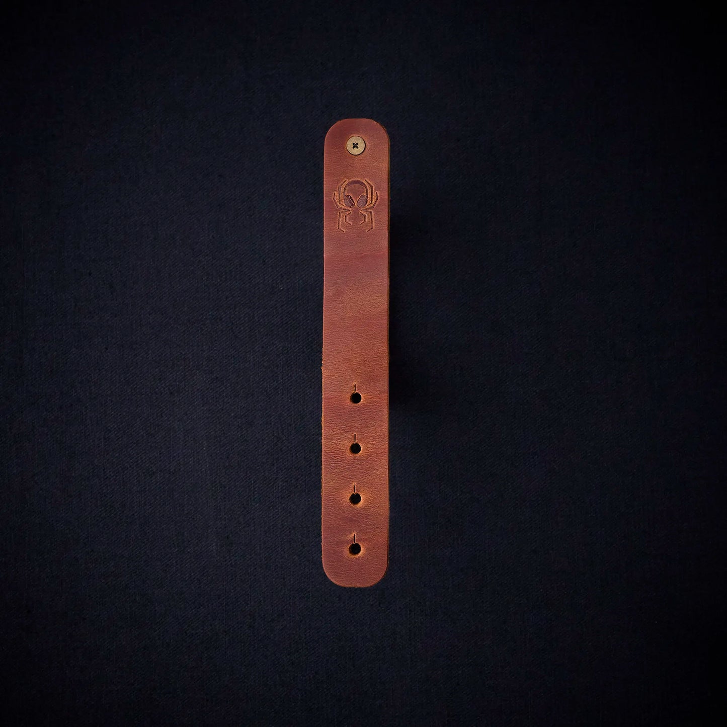 Fermata leather cable organizer in Sienna (light brown) with brass stud and embossed Arachne spider