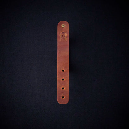 Fermata leather cable organizer in Sienna (light brown) with brass stud and embossed Arachne spider