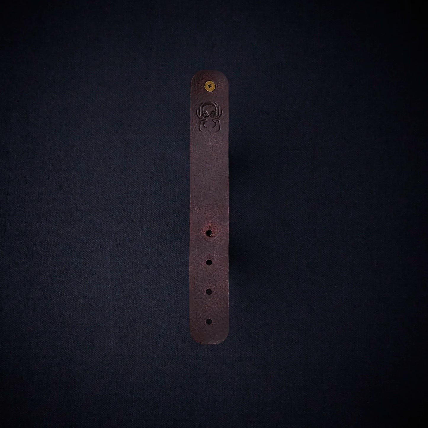 Fermata leather cable organizer in Tobacco (tobacco brown) with brass stud and embossed Arachne spider