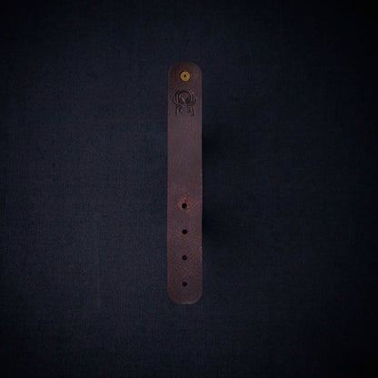 Fermata leather cable organizer in Tobacco (tobacco brown) with brass stud and embossed Arachne spider