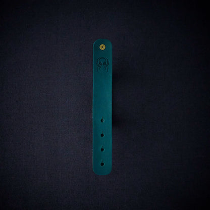 Fermata leather cable organizer in Verdigris (teal) with brass stud and embossed Arachne spider